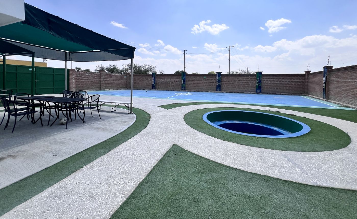Áreas comunes al aire libre con comedor techado, jardines y cancha