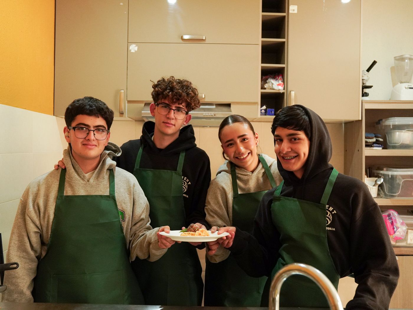 Alumnos de BATENT con mandil mostrando un platillo en el laboratorio de cocina