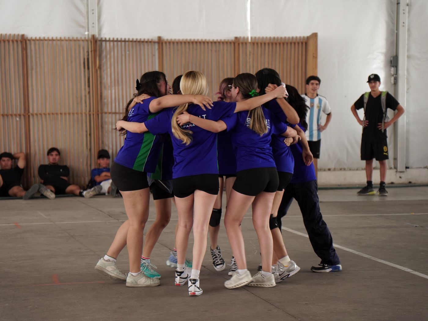 Equipo femenil de voleibol de BATENT celebrando abrazado